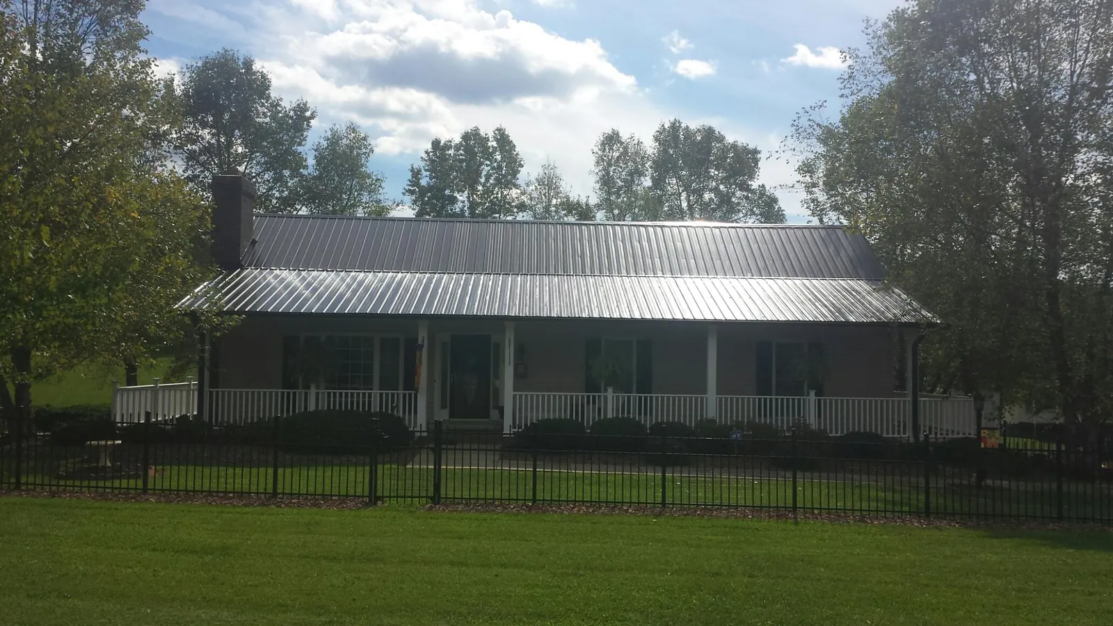 Gray metal roof on a brick ranch with a full width front porch — Gutter Guard Installation work by our crew in Round Mountain