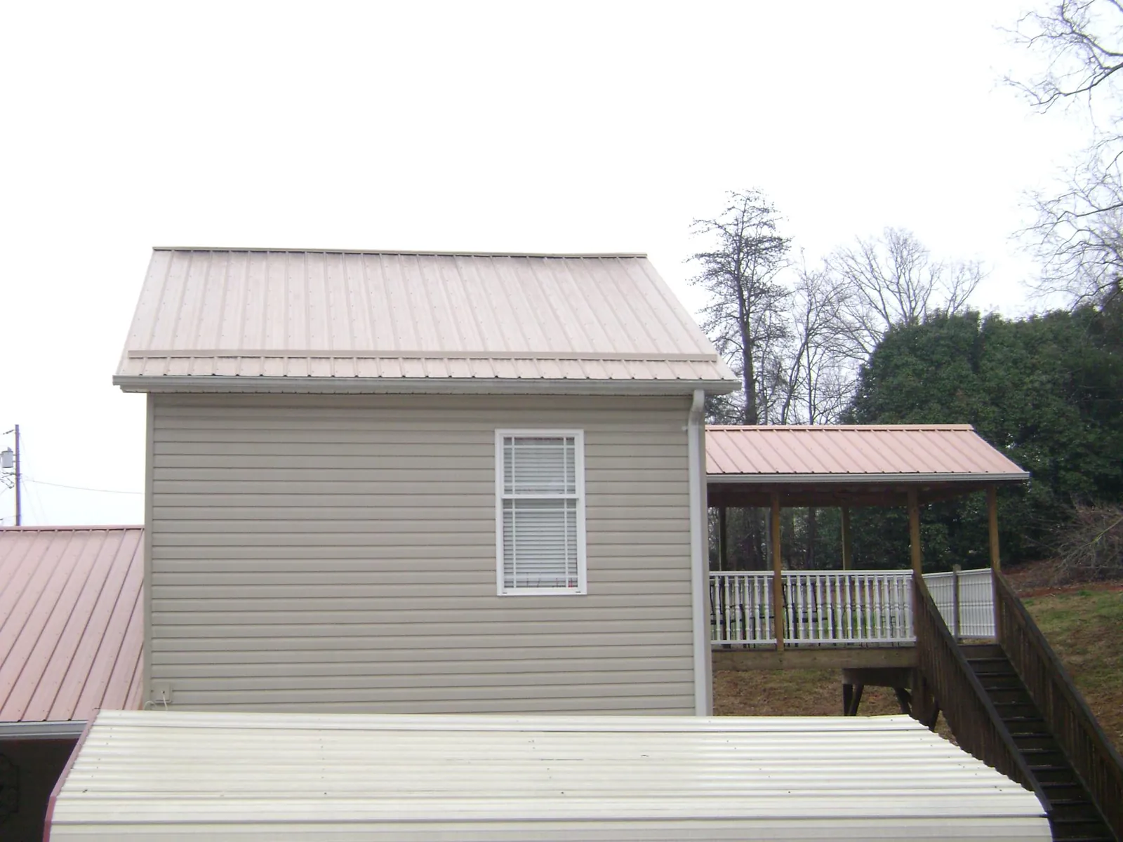 Tan metal roofs on a two story addition and attached porch, from a Roof Replacement job in Round Mountain